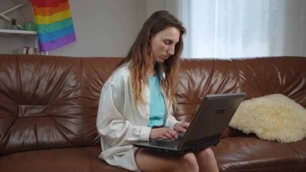 Seorang Gadis Mengetik Papan Ketik Laptop Sambil Duduk Sofa Kulit — Stok Video