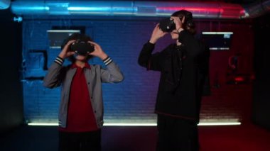 İki genç, VR bardaklarını kaldırır ve beşlik çakar, birbirlerine bakar ve gülerler. Gençler kafalarında sanal gerçeklik kasklarıyla loş bir odada dikiliyorlar.