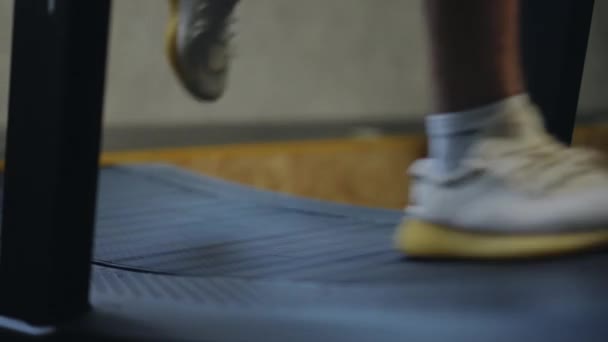 スローモーション ジムで屋内トレッドミルで走っているスポーツシューズの足のクローズアップ — ストック動画