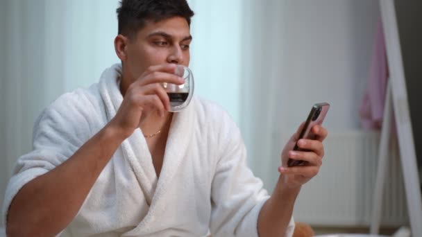 Slow Motion Young Man White Bathrobe Sits Bed Bedroom Drinks — Stock Video