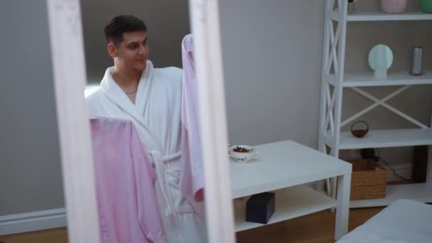 Floor Mirror Reflects Young Guy White Bathrobe Who Making Choice — Stock Video