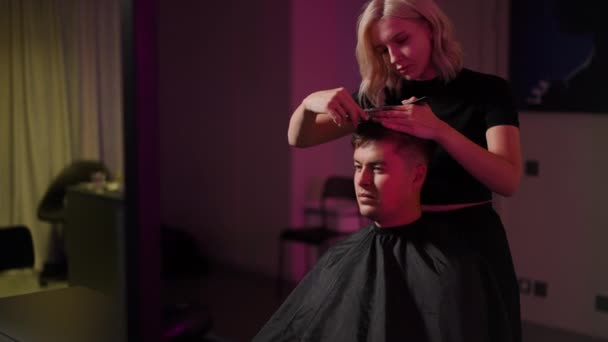 一个漂亮的女理发师用专业的剪子理发 女理发师用梳子和剪子做男人的发型 — 图库视频影像