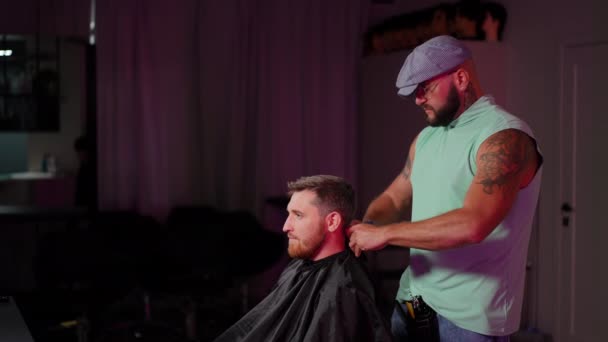 帽子の中のファッショナブルな男性の美容師は 美容椅子に座っている男性から髪を整える帽子を取り除きます スローモーション — ストック動画