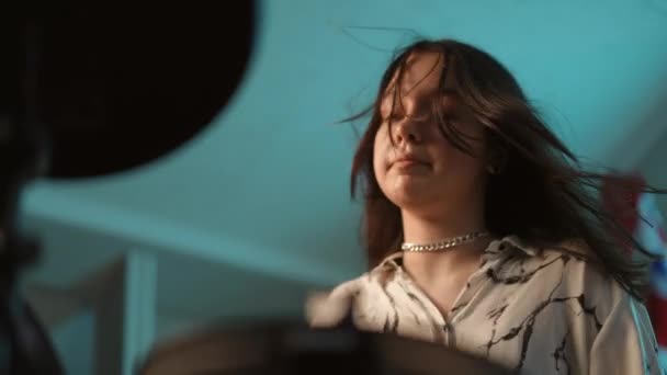 一个年轻有才华的女鼓手的脸 满脸汗珠 在一场充满活力的表演中 一个女孩坐在音乐学校里弹奏电子鼓 — 图库视频影像