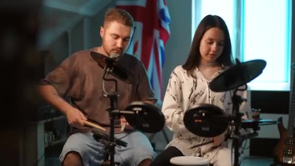 一位男教师和一位有抱负的女鼓手坐在一所现代音乐学校的教室里 同时在电子鼓上演奏 — 图库视频影像