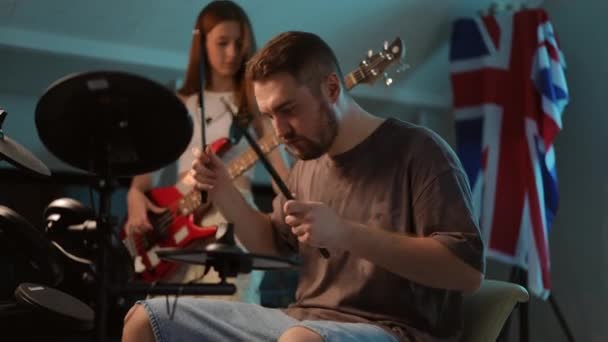 慢动作特写 一个男人坐在那里弹奏电子鼓 一个年轻的女孩弹奏低音吉他 音乐学校排练时的节拍 — 图库视频影像