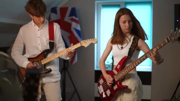 現代音楽学校でのギターデュエットのリハーサル 若い男が手にピックアップし エレクトリックギターを演奏し 女の子がベースギターを演奏する — ストック動画