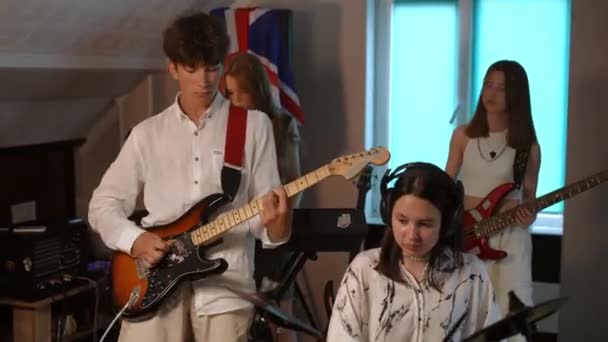 4人のミュージック グループが音楽学校でリハーサルをしている ミュージシャンはイギリスのロックバンドのヒットをリハーサルし 壁にイギリスの旗を掲げた部屋に立った — ストック動画