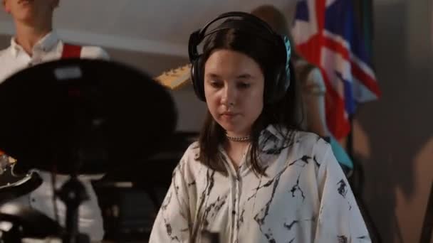 학교의 스튜디오에서 리허설에서 뮤지컬 전경에서 헤드폰을 착용하는 소녀는 키트를 연주합니다 — 비디오