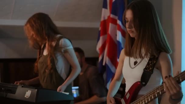 학교의 스튜디오에서 리허설에서 뮤지컬 소녀는 베이스 기타를 연주하고 하나는 합성기를 — 비디오