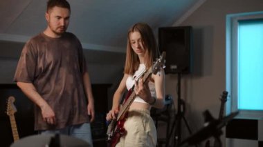 Ağır çekim. Bir kız gitarist bas gitar çalar ve müzik okulundaki bir prova sırasında akıl hocasının talimatlarını dinler.
