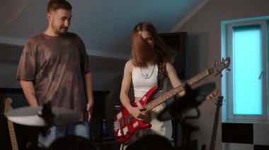 Bir erkek öğretmen gitar çalma tekniğinin karmaşıklığını kız öğrencisine açıklar, kız öğrencisine, gitar çalarken hızlı bir şekilde başarılı olamıyor, bir müzik okulunun odasında duruyor.