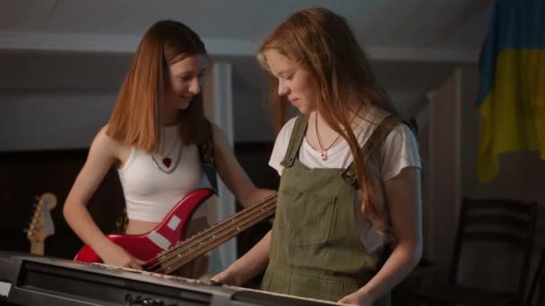音楽学校の授業中に2人の可愛い女の子がいました 女の子 ベースギターとシンセサイザーを再生するための右のメロディを選択 — ストック動画