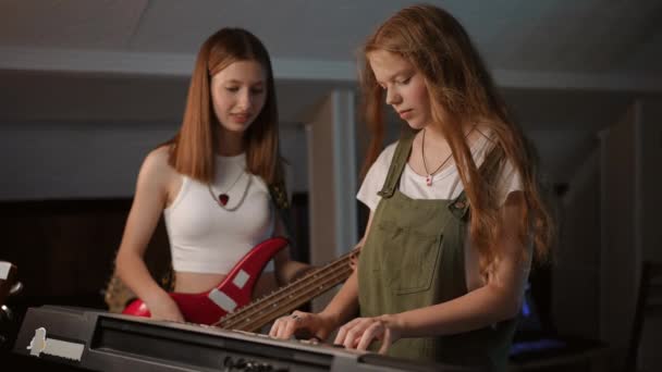 スローモーション 音で実験するシンセサイザーとベースギターの女の子は これはリハーサル中に笑いを引き起こします — ストック動画