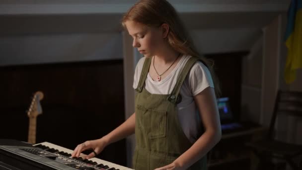 一个长头发的女孩站在音乐教室里弹奏合成器时出错了 — 图库视频影像