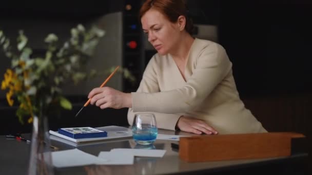 Ciężarna Kobieta Maluje Kartkę Okolicznościową Pędzlem Farbami Akwarelowymi Siedząc Przy — Wideo stockowe