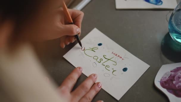スローモーション ショットオーバーショット 女性は ブラシと水彩画のペンキでイースターの挨拶カードに卵を塗ります Diyイースターカード — ストック動画