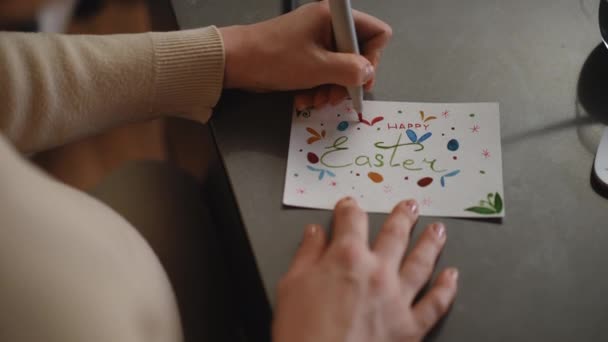 クローズアップ 妊娠中の女性は赤いマーカーでイースターの挨拶カードを描き リビングルームのテーブルに座っている間にカメラに示します Diyイースターカード — ストック動画
