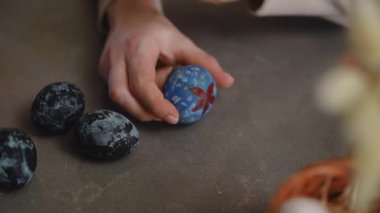 Yakın plan. Bir kadın Paskalya yumurtasına sarı suluboya boya ile paskalya resmi çiziyor. Paskalya kutlaması için hazırlıklar