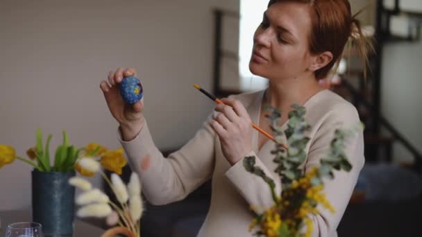 一个孕妇手里拿着一个复活节彩蛋 用画笔把上面的装饰品擦了一下 女人微笑着点点头 — 图库视频影像