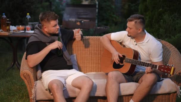 Muži Relaxují Venku Proutěné Pohovce Letního Večera Jeden Mužů Hraje — Stock video