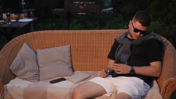 Mężczyzna Okularach Zasnął Siedząc Wiklinowej Sofie Letni Wieczór Świeżym Powietrzu — Wideo stockowe