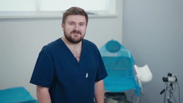 Dobroduszny Lekarz Brodą Niebieskim Mundurze Medycznym Patrzy Kamerę Skrzyżowanymi Rękami — Wideo stockowe