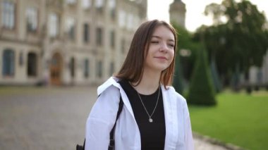 Ağır çekim. Bir kız enstitü parkında eski güzel bir binanın arka planına doğru yürüyor. Güneşli bir yaz gününde uzun saçlı, gülümseyen genç bir kız parkta yürüyor. Yürürken