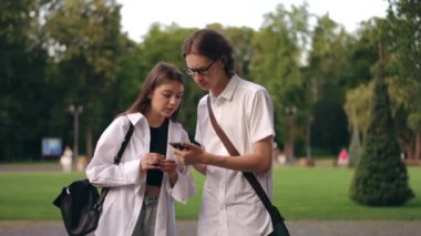 Adam kıza cep telefonunun ekranını gösteriyor ve birlikte bakıyorlar. Şehir parkında duruyorlar. Ekrandaki bilgiyi görünce, kız elleriyle yüzünü kapatıyor, adam seviniyor.