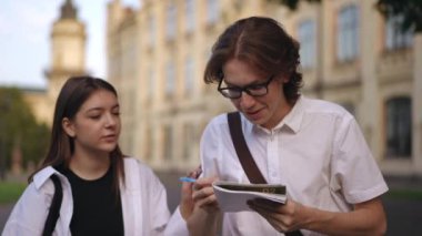 Bir adam elinde kalemle enstitü binasının yanında duran bir not defteriyle yazıyor. Arkadan bir kız geliyor. Öğrenciler bir araya gelip gülümseyerek ve gülerek beşlik çakmaktan mutlu olurlar.