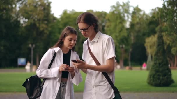 Fickó Megmutatja Mobilja Képernyőjét Lánynak Együtt Nézik Egy Városi Parkban — Stock videók