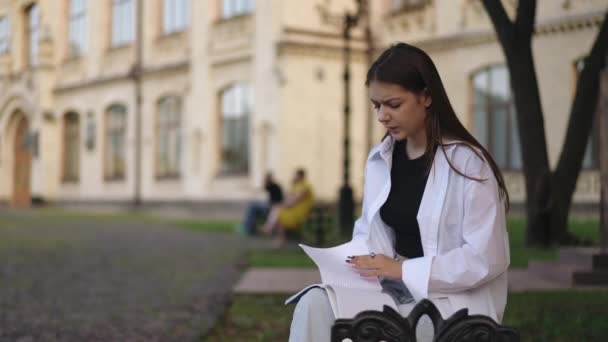 Ein Mädchen Sitzt Mit Einem Notizbuch Auf Dem Schoß Auf — Stockvideo