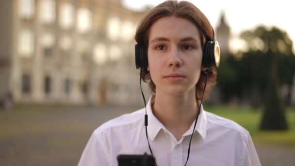 Joven Sostiene Teléfono Móvil Mano Escucha Música Los Auriculares Pie — Vídeo de stock