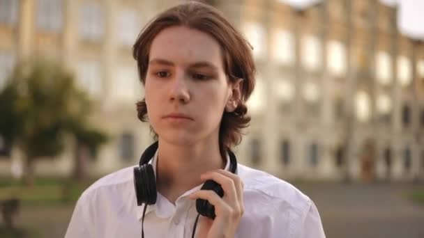Ένας Νεαρός Ακουστικά Γύρω Από Λαιμό Περπατά Και Σταματά Ένα — Αρχείο Βίντεο