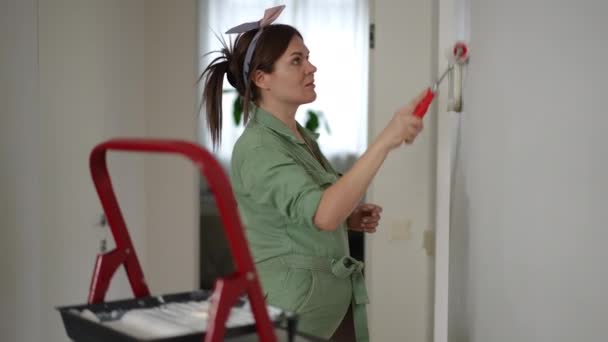 Uma Mulher Grávida Macacão Verde Habilmente Pinta Com Rolo Pintura — Vídeo de Stock