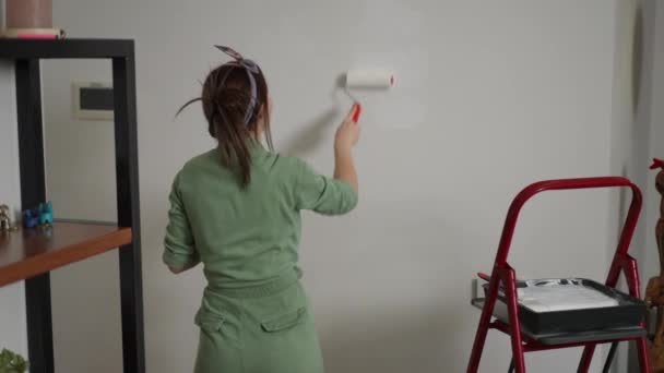 Widok Tyłu Kobieta Zielonym Kombinezonie Maluje Ścianę Tocząc Szeroki Wałek — Wideo stockowe