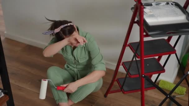 Uma Mulher Macacão Verde Senta Chão Madeira Perto Uma Escada — Vídeo de Stock