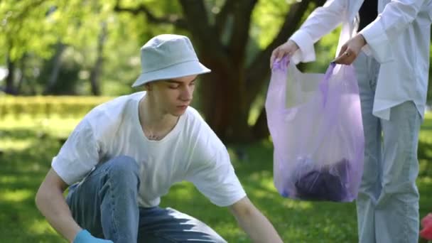 Chlápek Slunečním Klobouku Dřepící Sbírá Odpadky Roztroušené Trávě Parku Dává — Stock video