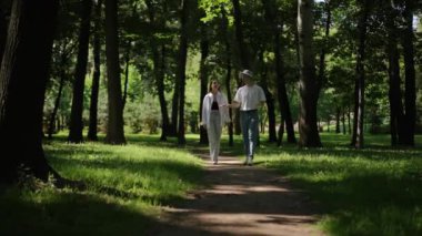 Güneş şapkalı bir adam ve uzun saçlı bir kız ormanda kirli bir yolda yürüyorlar ve birbirleriyle konuşuyorlar. Güneşli bir yaz gününde ormanda temiz havada bir yürüyüş.