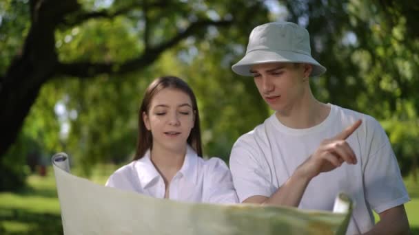 천천히 움직여 남자와 소녀가 펼쳐진 지도를 공원에서 식으로 하는지 논쟁하고 — 비디오