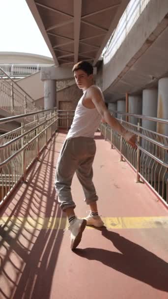 バーティカルビデオ スローモーション 若い男が踊るストリートダンス 街の歩行者橋の下で晴れた夏の日に踊る — ストック動画