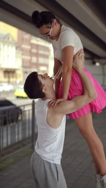 垂直录像 慢动作一个男人在街头跳舞时举起一个女孩的手 在夏天的一天和她在一座城市桥下跳舞 跳舞的夫妻喜欢跳舞 — 图库视频影像