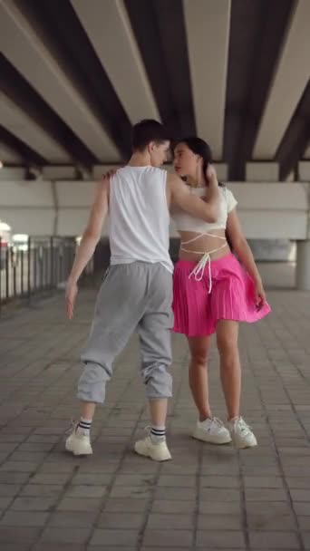 垂直录像 两个年轻有为的舞蹈家在城市桥下合唱街头舞曲 一个男人和一个女孩互相望着对方 在夏日的户外欢快地跳舞 — 图库视频影像