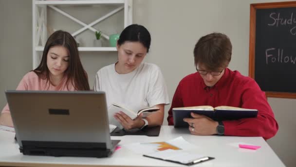 Een Man Twee Meisjes Bekijken Hun Collegeschriften Vergelijken Met Gegevens — Stockvideo