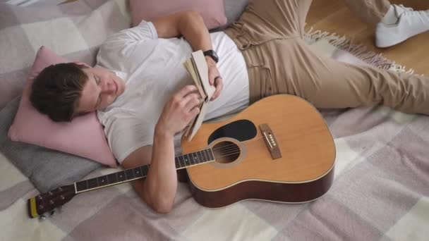 Vista Superior Tipo Está Leyendo Libro Abrazando Una Guitarra Con — Vídeos de Stock
