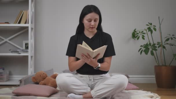 Dziewczyna Czarnej Koszulce Rzuca Książkę Uśmiecha Się Siedząc Pozycji Lotosu — Wideo stockowe