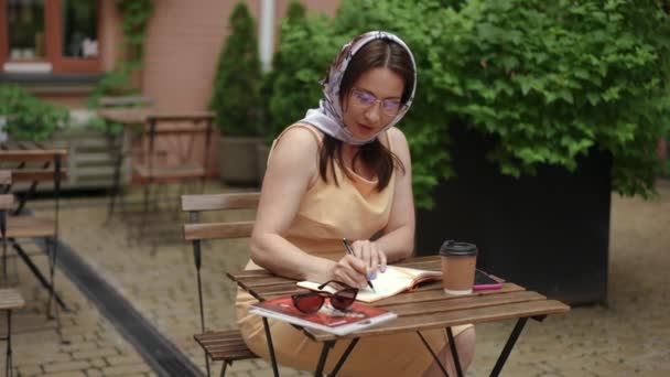 Gerakan Lambat Wanita Bergaya Berkacamata Menulis Dengan Pena Sebuah Buku — Stok Video