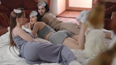 Kız yatak odasındaki yatakta kız arkadaşlarıyla yatarken büyüleyici bir hikaye anlatıyor. Başlarında gümüş uyku maskeleri olan genç kadınlar ve beyaz bir Spitz köpeği dikkatle dinleyin.