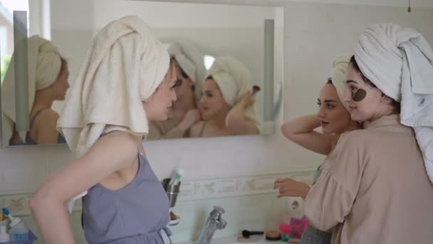 女人在化妆的时候喜欢说闲话 头戴毛巾的年轻女性并不讨厌在身边谈论朋友 即使是在她们做晨妆的时候 — 图库视频影像