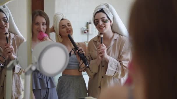 아름다운 친구는 화장실에 서있는 메이크업을하는 콘서트를 제공합니다 소녀들은 거울을 즐겁게 스톡 푸티지